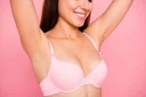 Woman in pink bra raising her arms after a breast lift in Philadelphia, PA