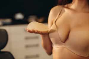 Woman in bra holding breast implant for breast augmentation in Philadelphia, PA